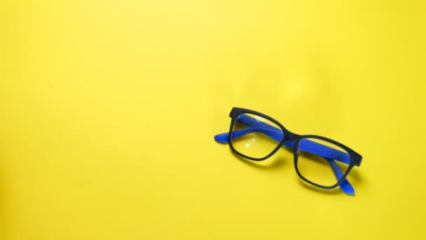 Human hands search, find and take eye glasses in blue plastic frame. On yellow background. — Stock Video
