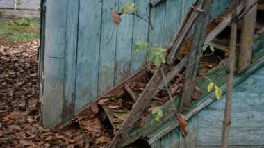 Terk edilmiş, harap olmuş eski ahşap bir ev. Merdivenler ve kapılar. Kurumuş yapraklarla ve yıpranmış boyalarla dolu. Yakın plan. Açık havada..
