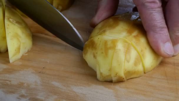 İnsan elleri, çorba pişirmek için tahta kesme tahtasının üzerinde keskin mutfak bıçağıyla çiğ patatesleri dilimlere ayırır. Hazır vejetaryen sağlıklı yiyecekler. Yakın plan.. — Stok video
