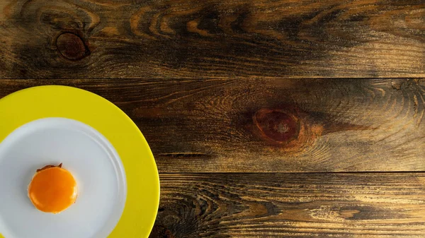将蛋黄放在圆形陶瓷盘上 在粗糙的木制背景或桌子上有黄色边缘 复制文本的空间 上下颠倒平躺在床上16X9格式 靠近点室内环境 — 图库照片
