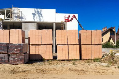 Kiremitleri, tuğlaları ve kulübe inşaatının yanında inşaat ekipmanları olan birkaç yığın. Yakın plan. Açık havada..