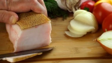 Şefin elleri domuz yağını keskin mutfak bıçağıyla ahşap mutfak tahtasına kesti. Taze sebze, domates, soğan, dereotu, sarımsak. Yakın plan..