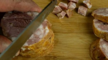 Aşçı salamı büyük mutfak bıçağıyla pizza ya da sandviç için tahta kesme tahtasıyla keser. Domuz eti dilimleme sahnesinin yakından görüntüsü. Yakın plan..