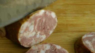 Aşçı salamı büyük mutfak bıçağıyla pizza ya da sandviç için tahta kesme tahtasıyla keser. Domuz eti dilimleme sahnesinin yakından görüntüsü. Yakın plan..