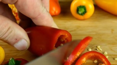 Aşçı ahşap mutfak kesme tahtasına büyük mutfak bıçağıyla tatlı biber keser. Sabit kapak dilimlenmiş. Dilimlenen dolmalık biberin yakın plan görüntüsü. Sağlıklı beslenme konsepti. Diyet yemek. Yakın plan..