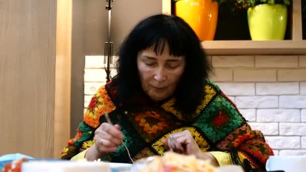 Hungrige ältere erwachsene Frau kaukasischer Herkunft in heller Kleidung, die gierig eine Menge leckeres und abwechslungsreiches Essen zu sich nimmt, am Tisch im Speisesaal oder Restaurant sitzt. Nahaufnahme. — Stockvideo