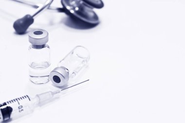 Uyuşturucu ya da aşı, 3 ml plastik şırınga ile iğne ve beyaz arka plan üzerinde mavi rengi izole stetoskop odak dışı şişe