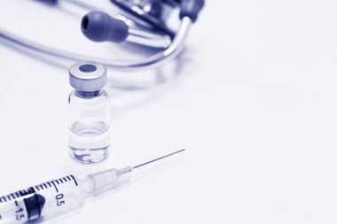 Uyuşturucu ya da aşı, 3 ml plastik şırınga ile iğne ve beyaz arka plan üzerinde mavi rengi izole stetoskop odak dışı şişe