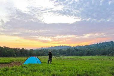 Çayırdaki çadırın yanında duran adam.