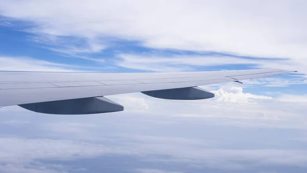 Wing of airplane fly over  the blue sky and white cloud