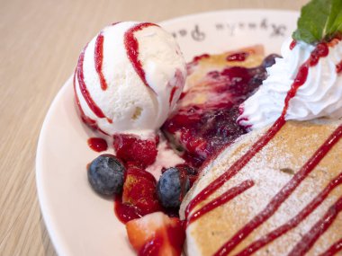 Dondurma ve krep yerken üzerine çeşitli berry meyve ile beyaz yemek, tatlı (seçici odak restoranda closeup)