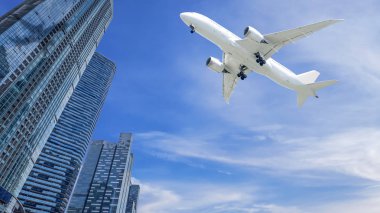 Modern kentin mavi gökyüzü ve beyaz bulut kopya alanı ile bina üzerinde uçan uçak