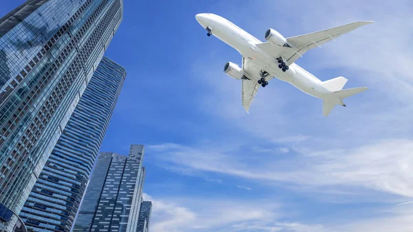 青い空と白い雲コピー スペースの都市で近代的な建物上空を飛ぶ飛行機 — ストック写真