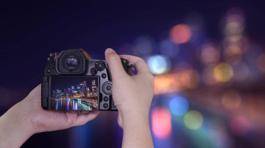 Kadın fotoğrafçı tutun alacakaranlık zamanda bokeh görünümün arka planında cityscape gece ışık Singapur Skyline ile fotoğraf çekmek için dijital fotoğraf makinesi