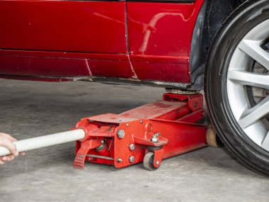 Mekanik mühendisi kırmızı araba garajda onarmak için kirli kırmızı Hidrolik zemin jack kullanın