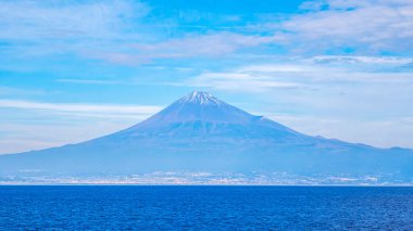 Fuji Dağı 'nın mavi gökyüzü üzerindeki manzarası ve Japonya' nın Shizuoka kentindeki Suruga Körfezi 'ndeki feribot teknesinden gelen beyaz bulut.