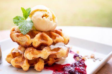 Waffle ve vanilyalı dondurma tabakta ahududu sosu, restoranda tatlı.)