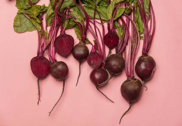 Group of beetroots with leafs on pink background. Above view