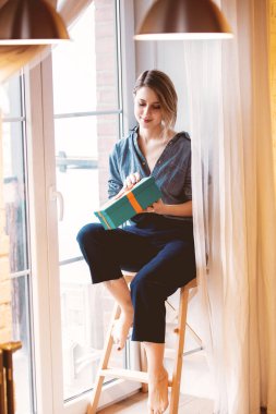 hediye kutusu penceresi yakınındaki küçük merdivenler evde oturup güzel kızıl saçlı kız.