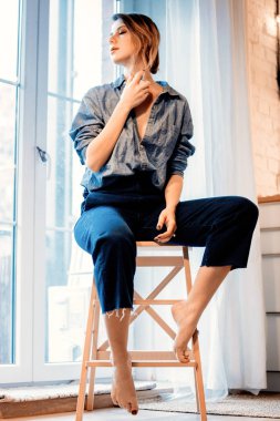 Parfüm ile parfümlü ve pencere yakınındaki küçük merdivenler evde oturup güzel kızıl saçlı kız. 