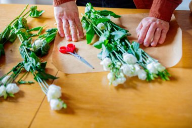 Adam beyaz gül mutfak masasının üzerinde kaydırma görünümünü kırpılmış. Kendi iş kavramı.