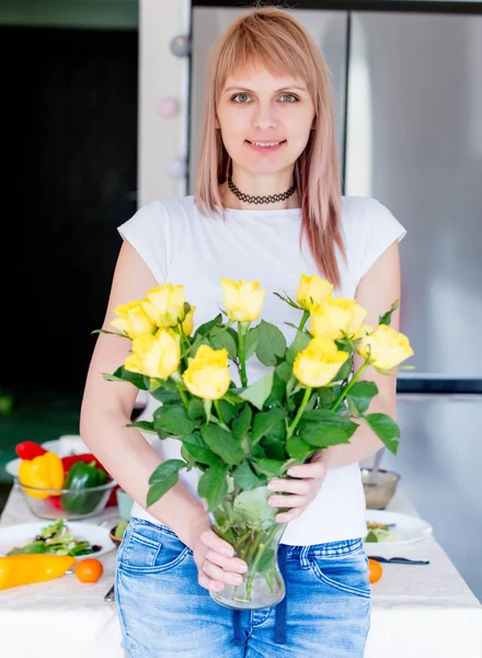 マザーズ デイでキッチンで黄色いバラを持つ若い女性 — ストック写真