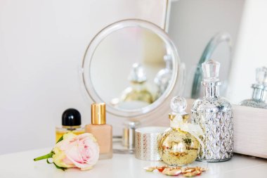 parfüm, cilt bakım kremi ve pembe zarf ve ayna bir tabloda yakınındaki gül ile diğer kozmetik.