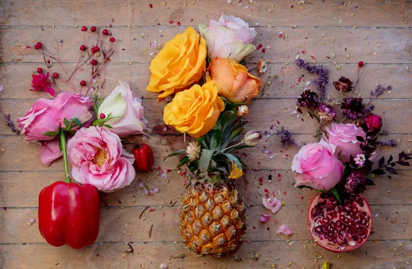 Pepper, pineapple and Pomegranate with roses decorated on wooden background.