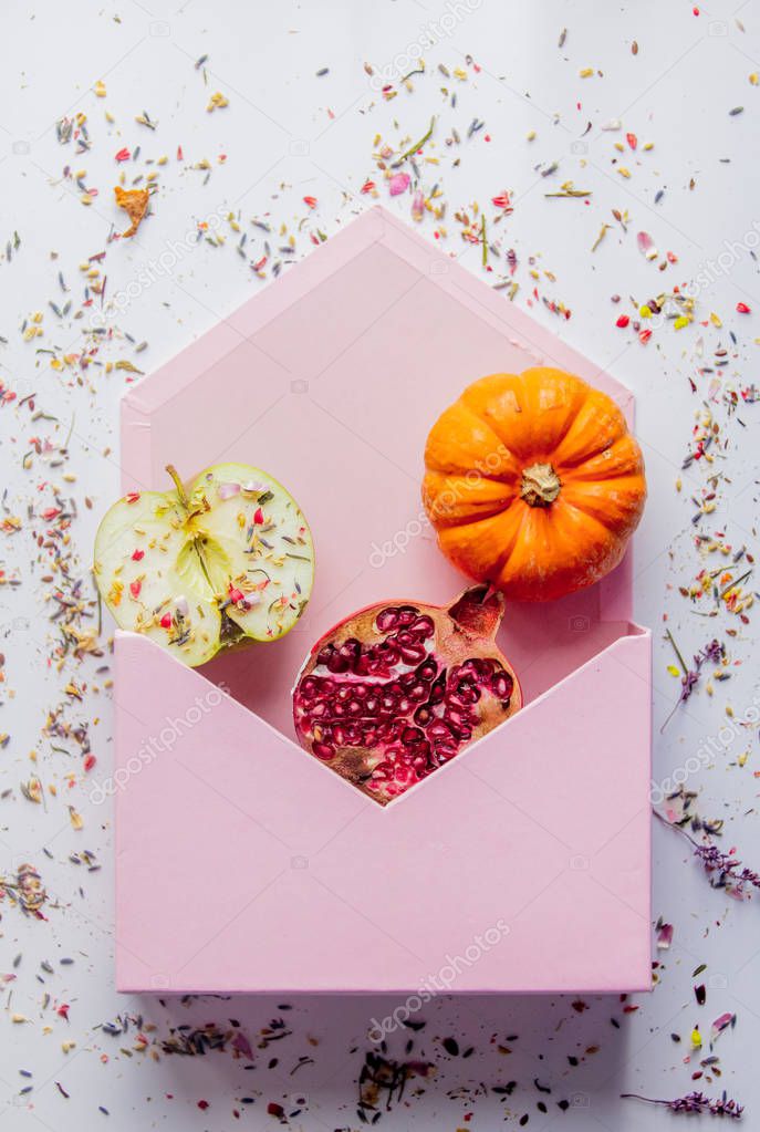 big envelope with apple, Pomegranate, pumpkin, lavender leaves and petals on white background. Above view
