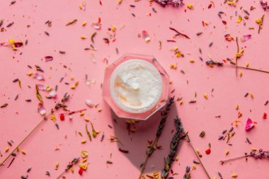 Lavanta çiçek yaprakları ve pembe bir arka plan yapraklarda bir kavanoza cilt bakım kremi