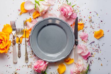 Tabak, çatal ve bıçak ile gül beyaz arka plan üzerinde. Bahar akşam yemeği kavramı 