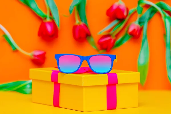 Gafas de sol, caja de regalo con lazo y tulipanes —  Fotos de Stock