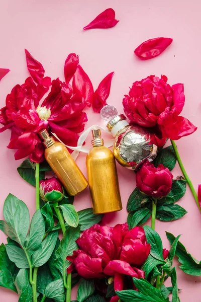 Peonías rojas frescas y frascos de perfume —  Fotos de Stock