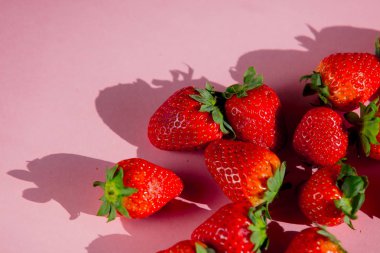 Pembe arka planda taze çilek grubu. Yukarıdaki görünüm