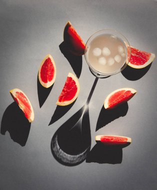 Glass with cocktail and cut grapefruits around  clipart