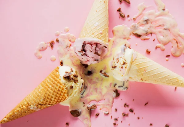 broken and spilled cream and chocolate ice-cream on pink background. Above view
