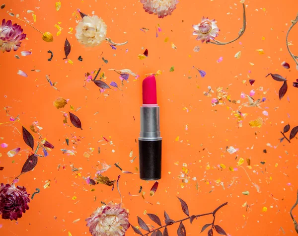 Trockenes Bäuchlein mit Blumen und rotem Lippenstift auf orangefarbenem Hintergrund — Stockfoto