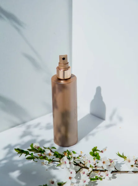 Бутылка духов и вишневая ветка с цветами — стоковое фото