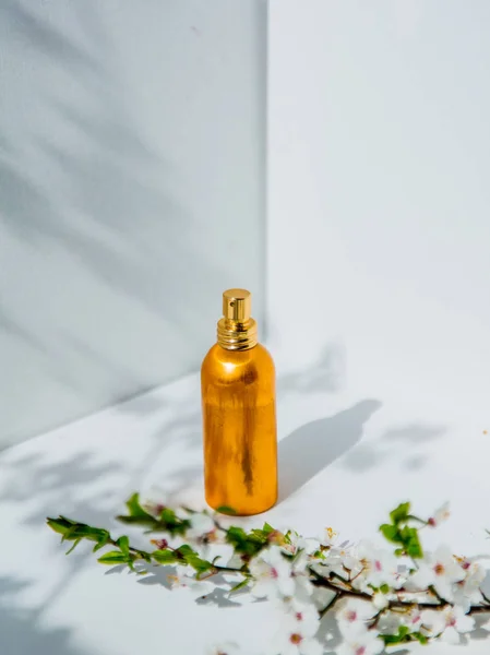 Botella de perfume y rama de cereza con flores — Foto de Stock