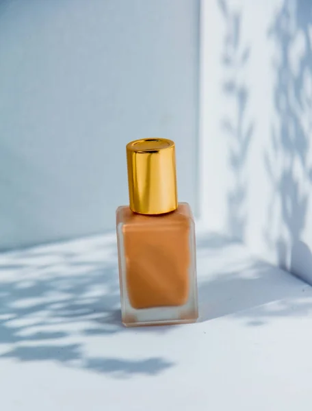 Фундаментний крем в золотій пляшці і тіні вишневого дерева — стокове фото