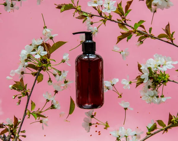 Бутылка с черным кремом и вишневые цветы — стоковое фото