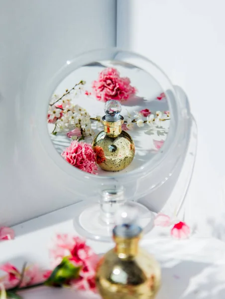 Frasco de perfume com flores de espelho e dianthus — Fotografia de Stock