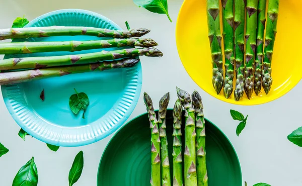 Asparagi freschi e foglie di basilico in piatti — Foto Stock