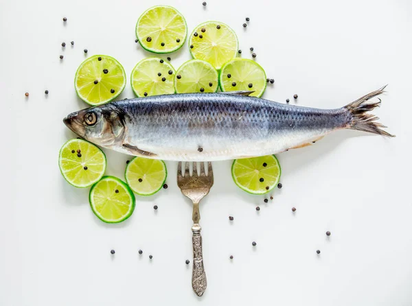 Fresh herring fish with lemons, peppers and fork — Stock Photo, Image