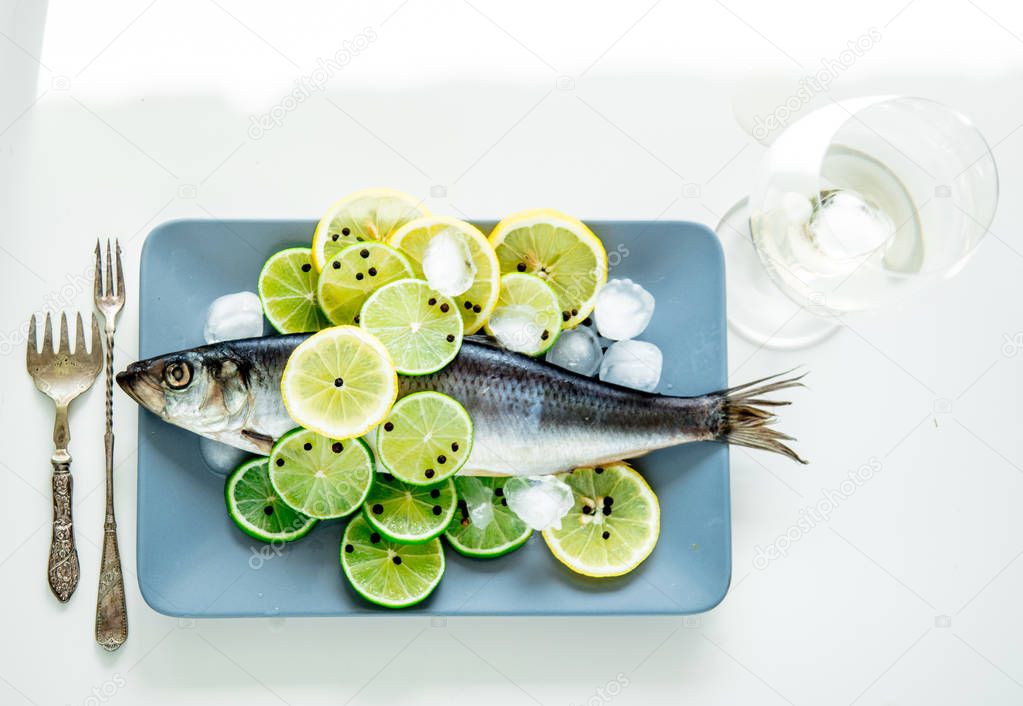 Fresh herring fish with lemons and peppers and wineglass