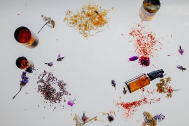 bir masada cam parfüm kapları yanında çiçek ve otlar