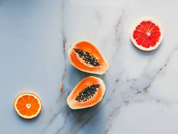 Свіжий зрізаний папайя зі стелями та апельсинами на мармуровій поверхні — стокове фото
