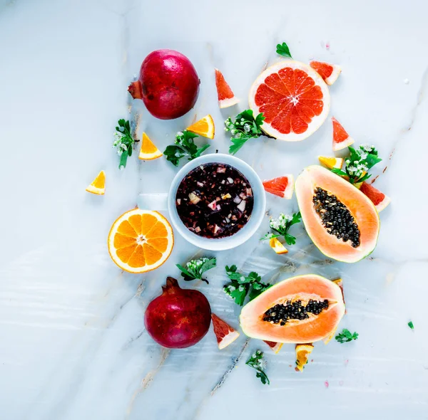 Свіжий зрізаний папайя зі стелями, гранатами, апельсинами біля чорної пляшки — стокове фото