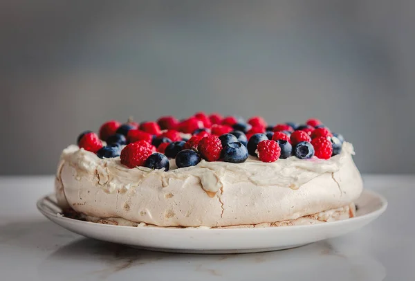 decorated cream pie with blueberries and raspberries on a table