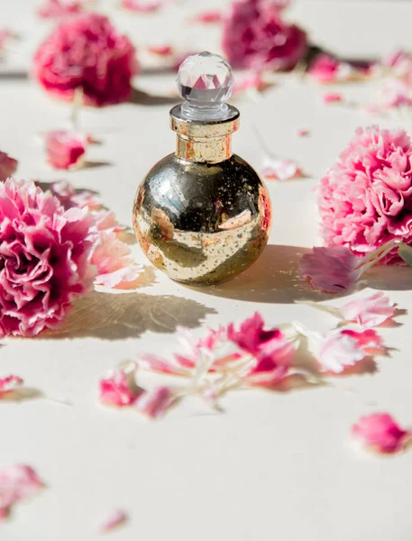 Dianthus bloemblaadjes en parfum fles met natuurlijke schaduwen — Stockfoto